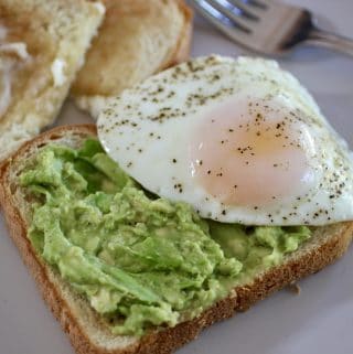 avocado toast with egg and extra toast and fork