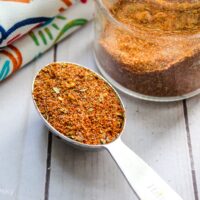 Taco seasoning in jar with table sppon on table with napkin