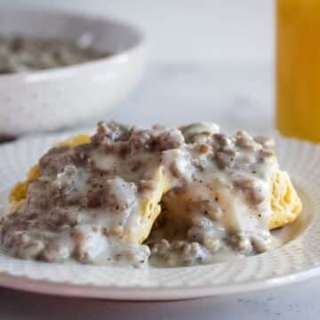 biscuits with gravy on plate with orange juice