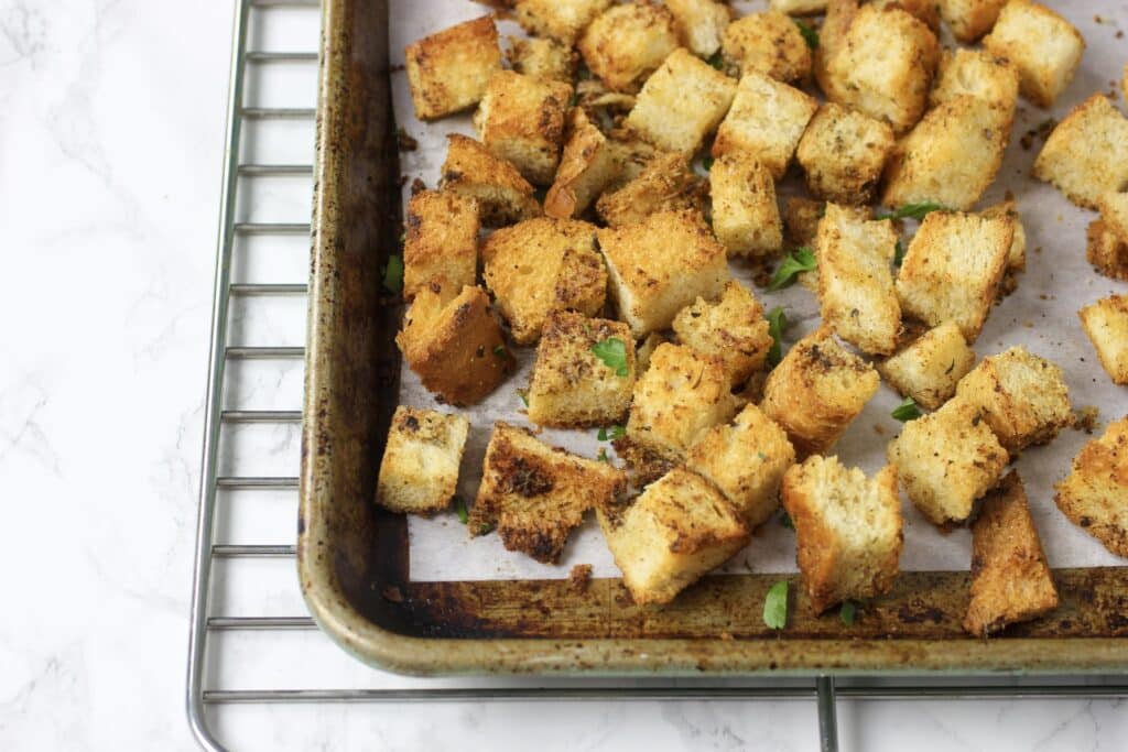 baked croutons on parchment paper and cookie sheet