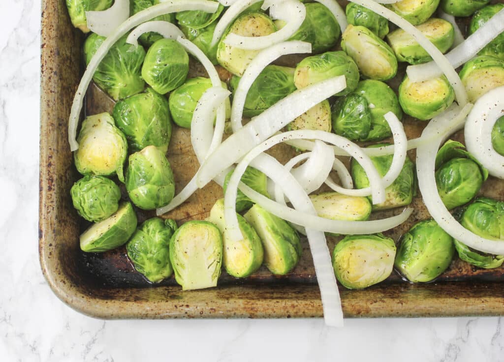 cut brussels sprouts and onion on sheet pan