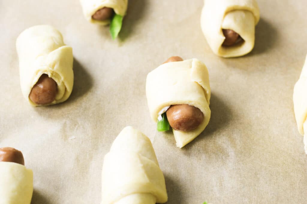 Crescent roll dough, little smokey, cream cheese and jalapeno rolled up on cookie sheet.