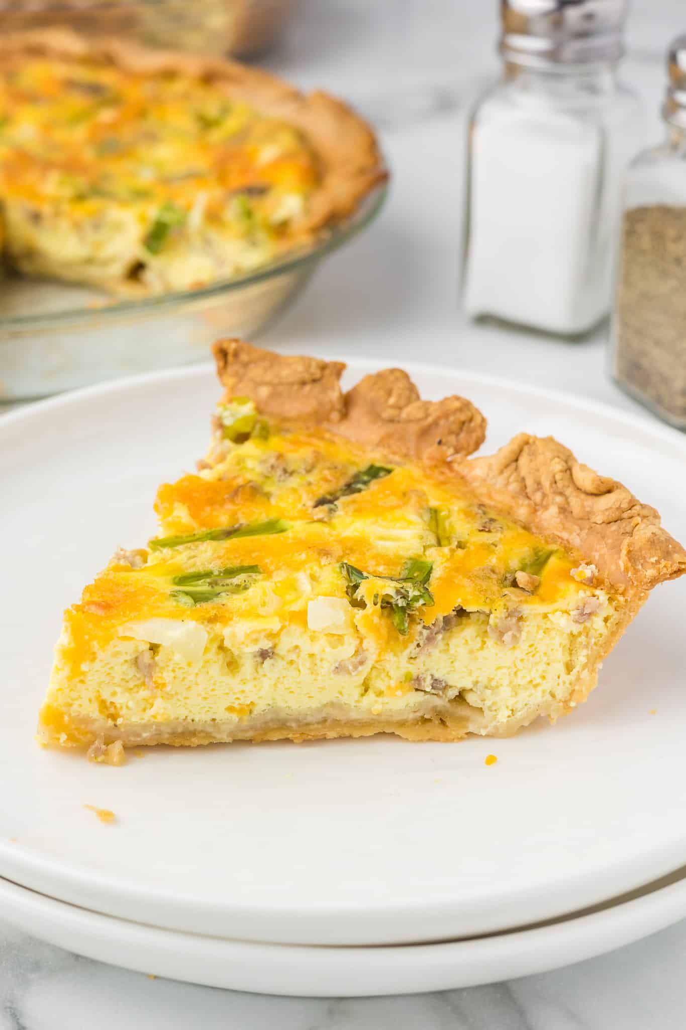 Sausage and asparagus quiche on a white plate.