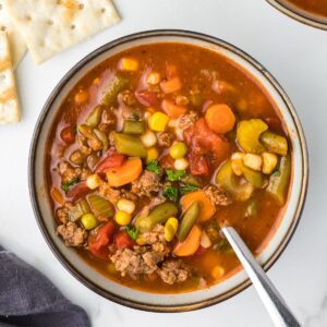 Hearty Hamburger Soup in a bowl with a spoon.