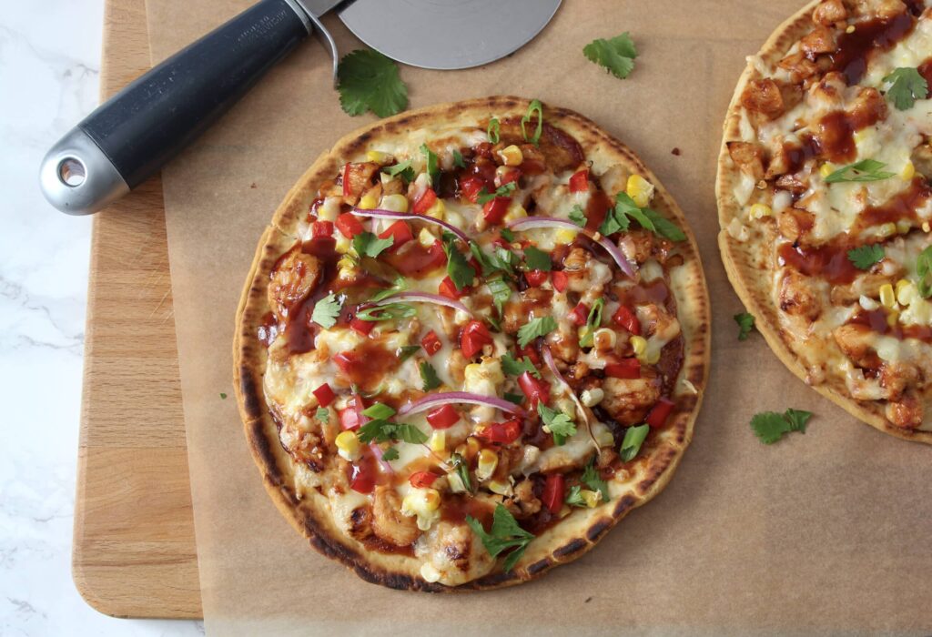 bbq chicken flatbread on parchment with pizza cutter
