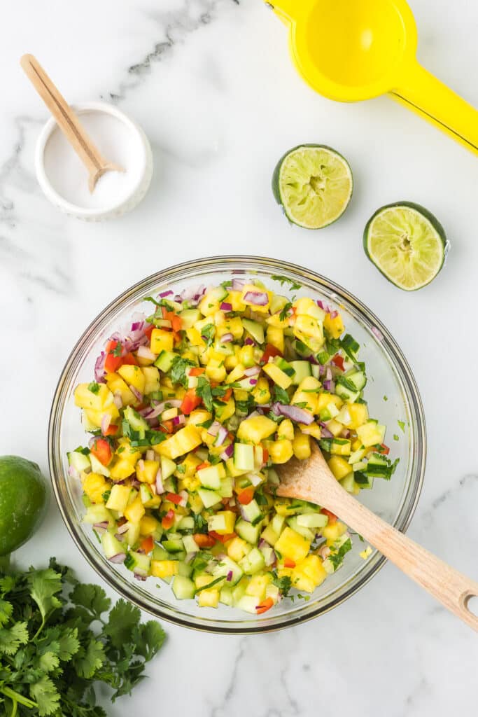 Jalapeno Pineapple Salsa mixed in a bowl with a wooden spoon.