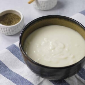 bowl of bechamel sauce with salt and pepper