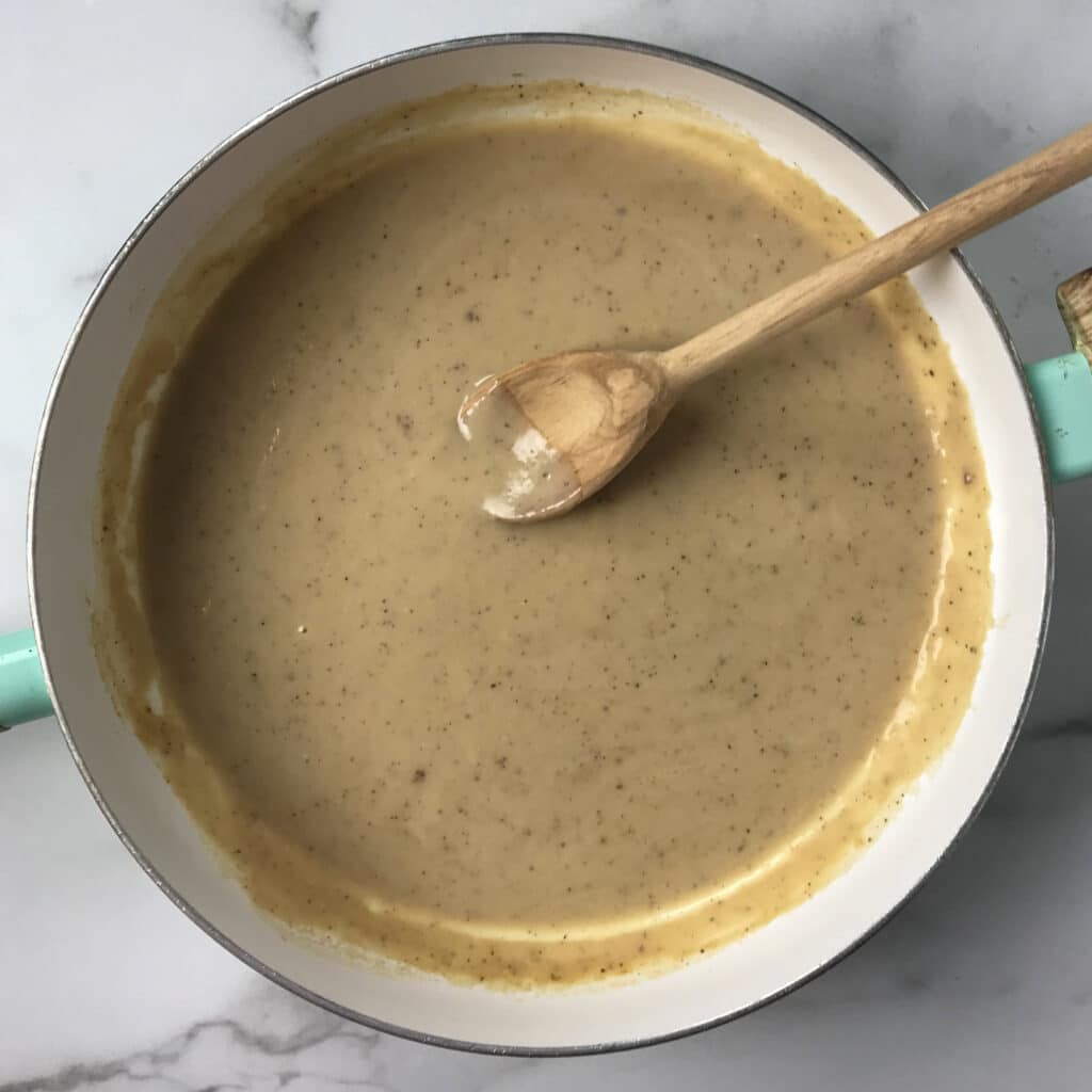 beef broth and milk to create cream sauce with wooden spoon in large skillet