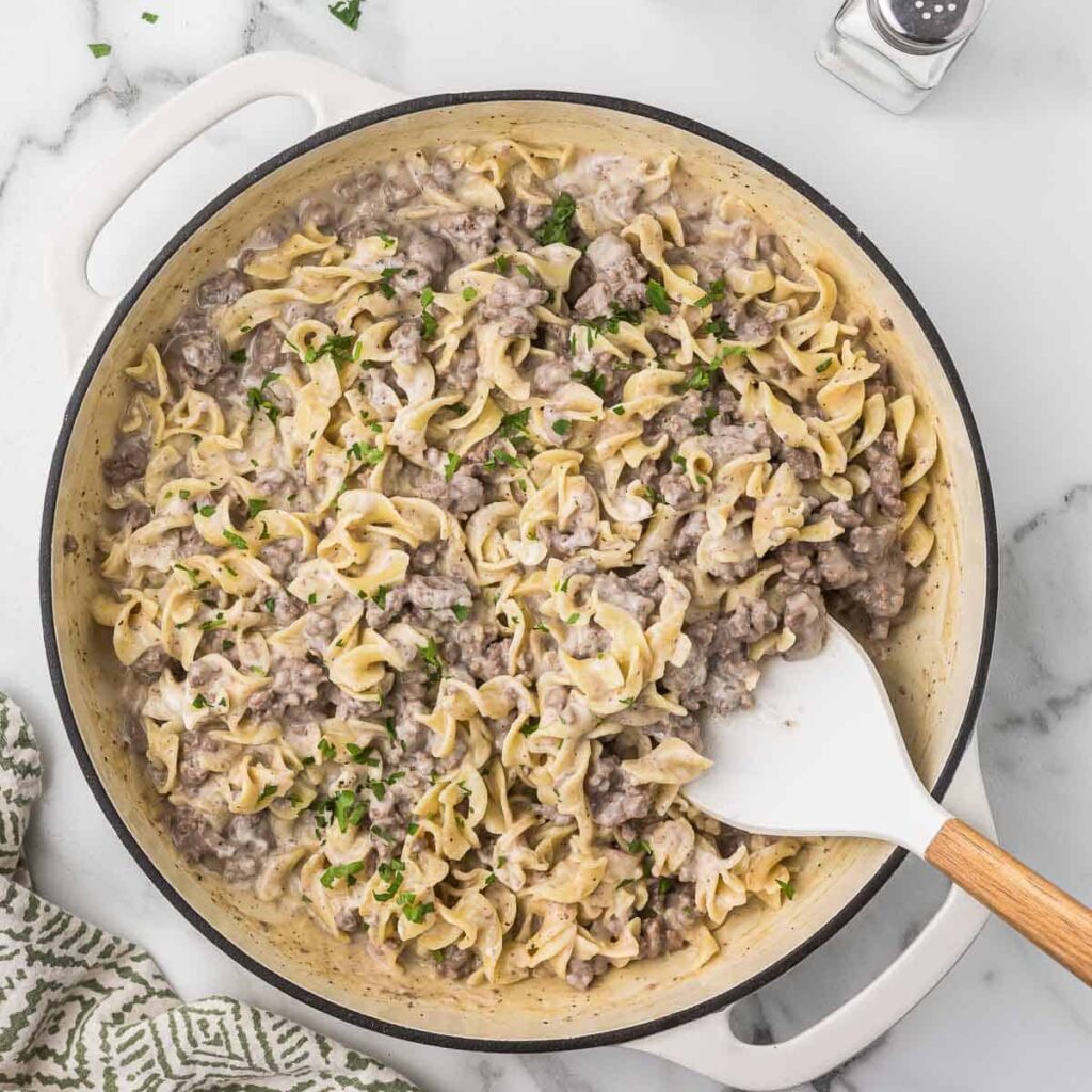 Ground Beef Stroganoff in a dutch oven with a spatula.