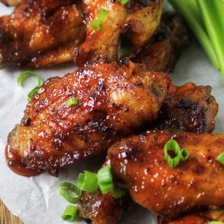 Honey bourbon chicken wings on plate with celery and green onions.