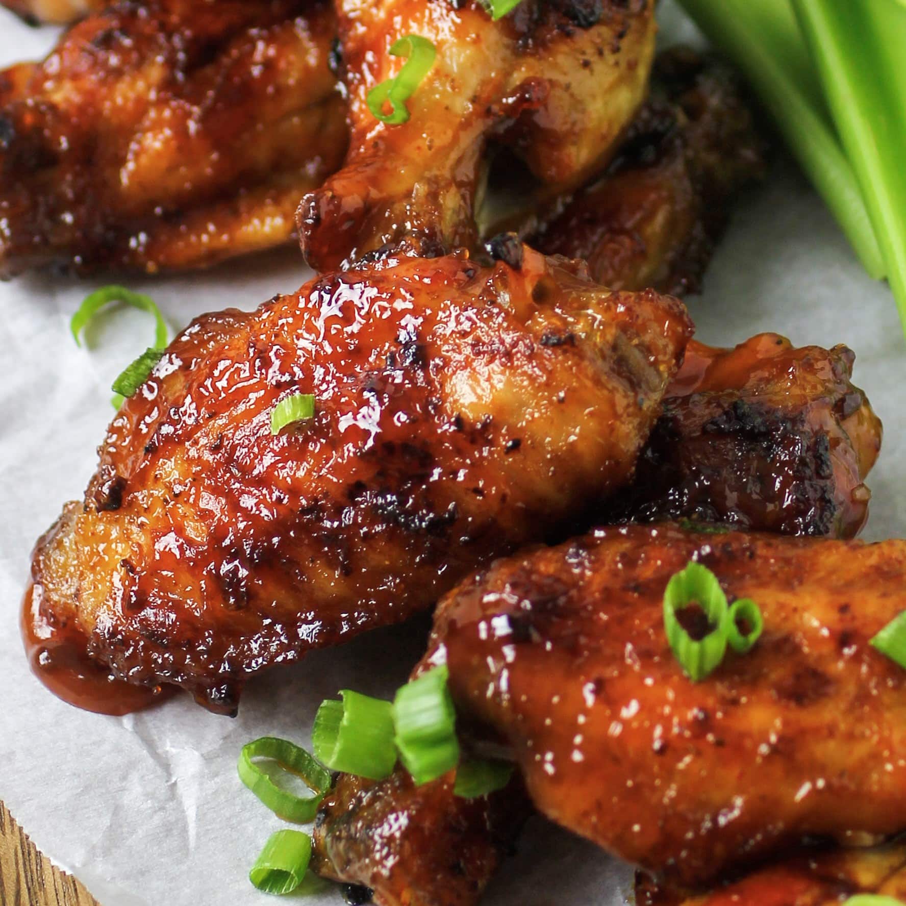 Honey bourbon chicken wings on plate with celery and green onions.