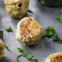italian chicken meatballs on a cookie sheet with basil