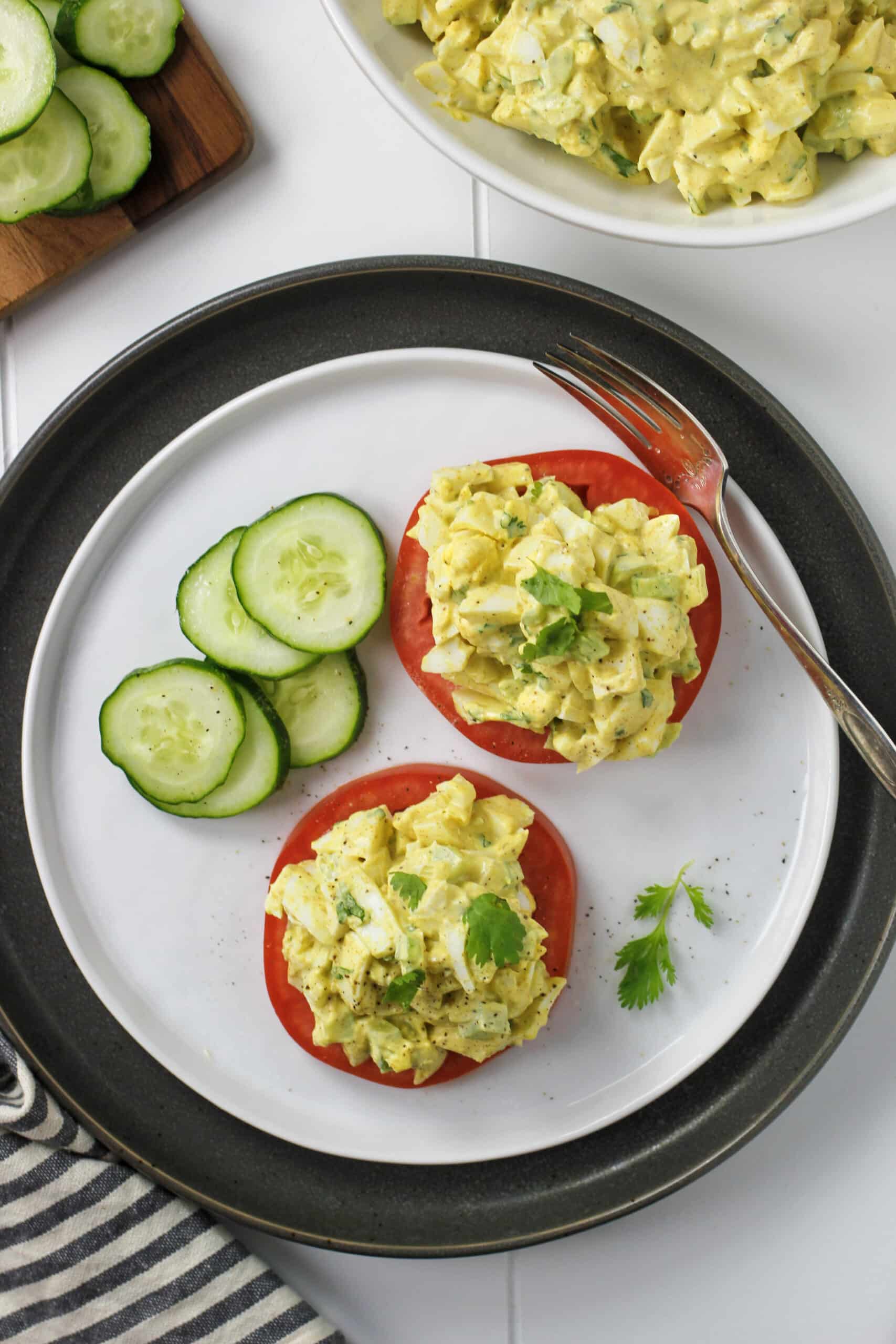 Curried egg salad on plate with sliced tomatoes and cucumbers.