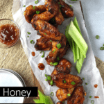honey bourbon chicken wings on a plate with extra plates for serving and celery