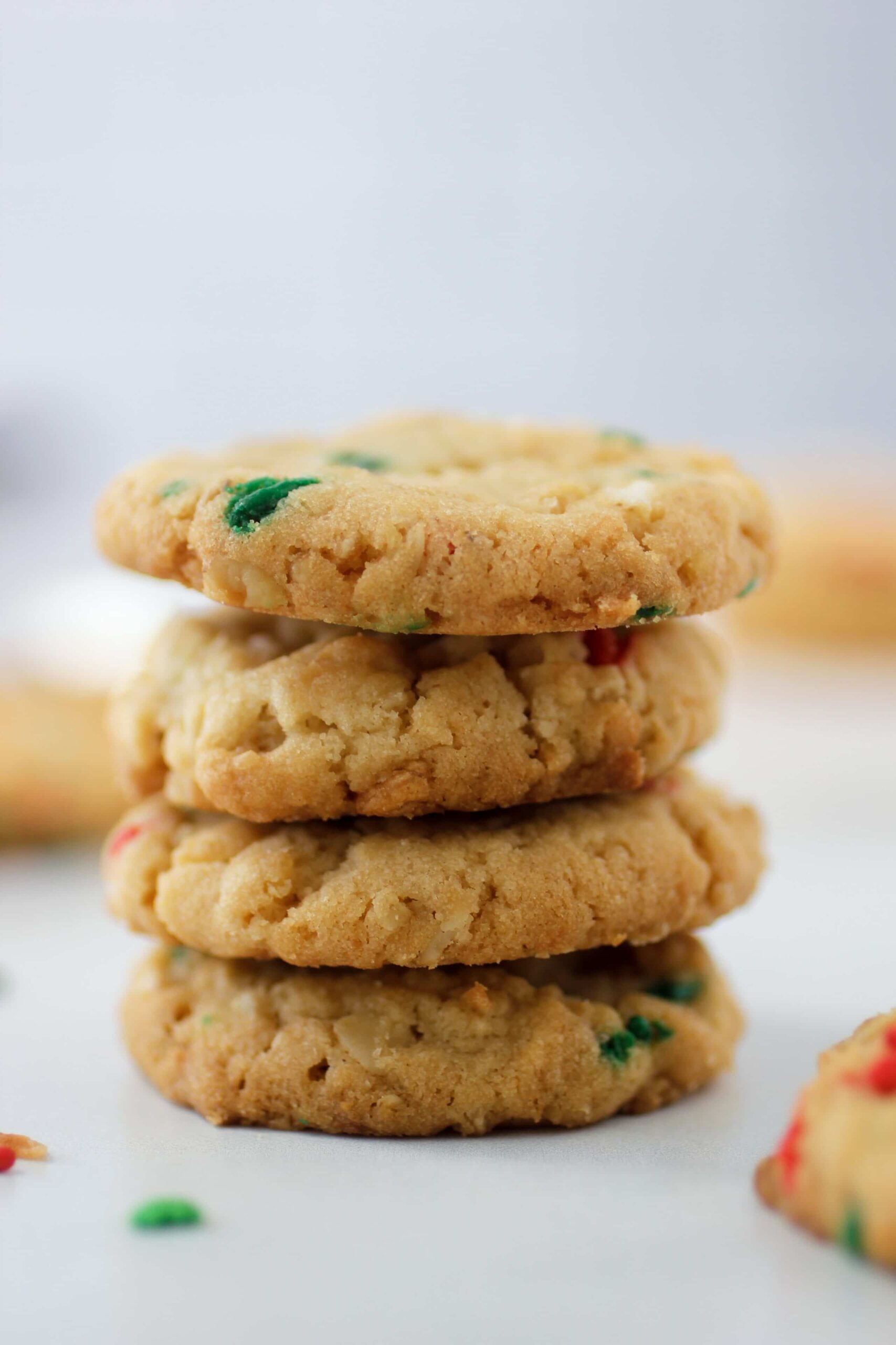 Crunchy sugar cookies with sprinkles four high on a white counter top.