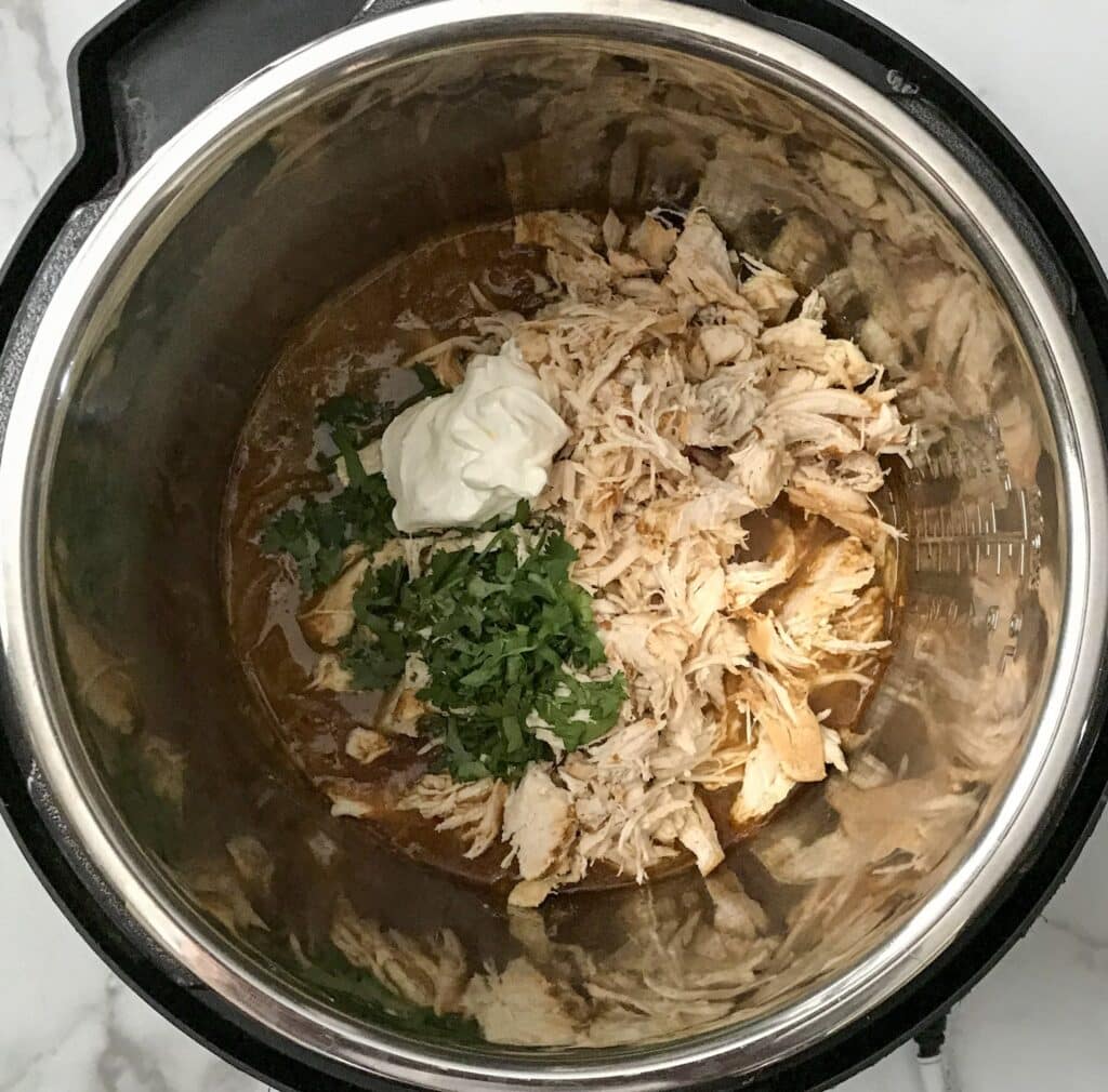 shredded chicken, salsa verde sauce with spices, sour cream and cilantro in an instant pot