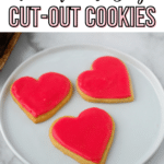 three heart shaped cookies on a plate with pink icing