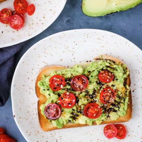 Avocado toast with tomatoes and balsamic glaze on plate.