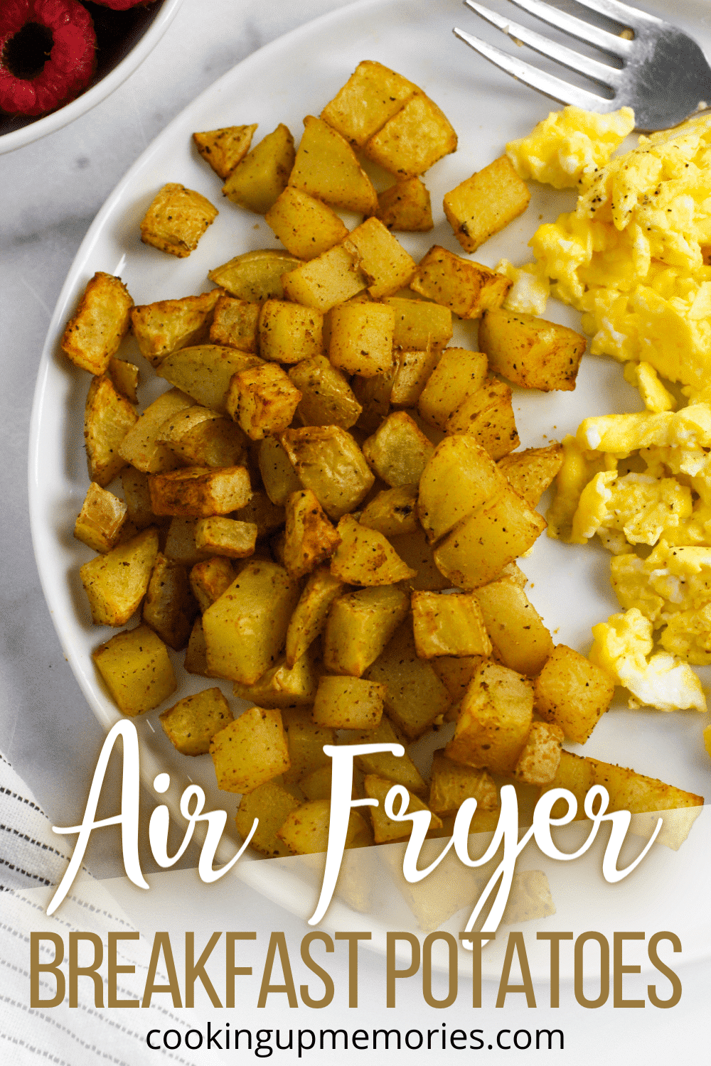 Air fryer breakfast potatoes on a white plate with scrambled eggs.