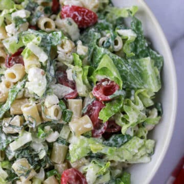 Caesar Pasta Salad with dressing in a white bowl.