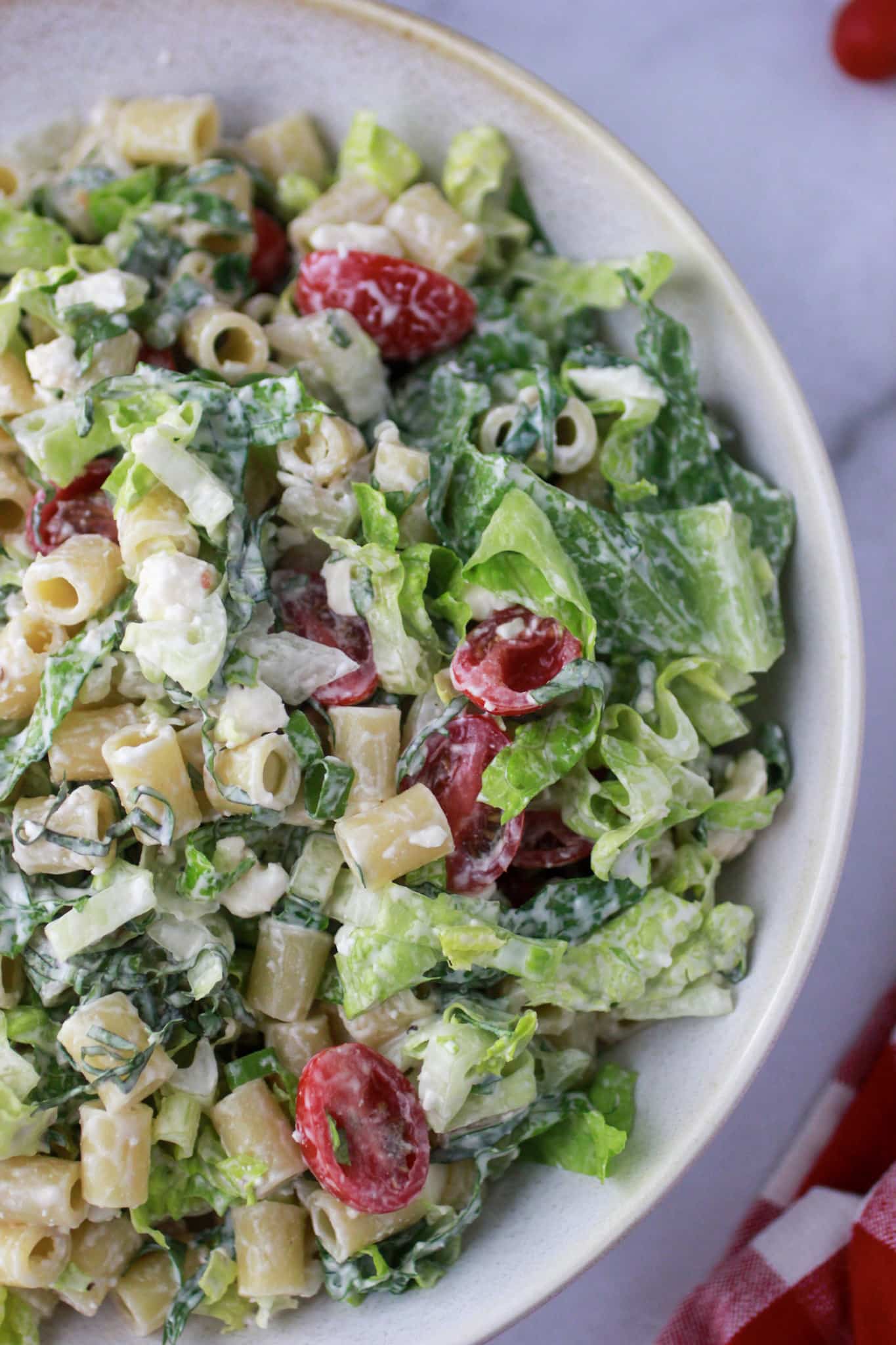 Caesar Pasta Salad with dressing in a white bowl.