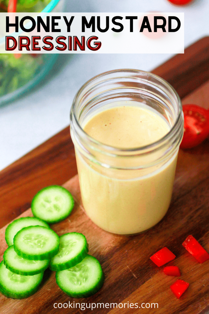 Honey Mustard Dressing in a mason jar with cucumbers and tomatoes.