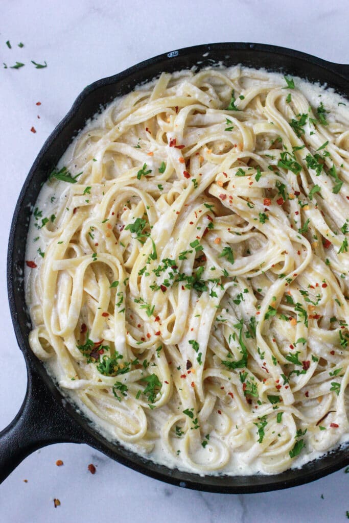Parmesan Alfredo Sauce tossed with fettuccine noodles and garnished with fresh parsley and red pepper flakes.