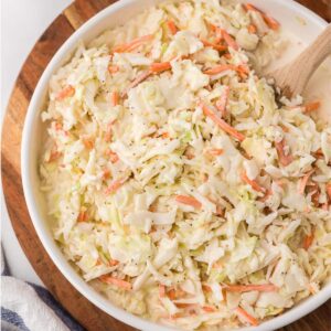 Creamy Sweet Coleslaw in a white bowl on a cutting board.