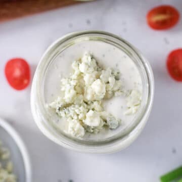 blue cheese dressing in a jar with garden vegetables.