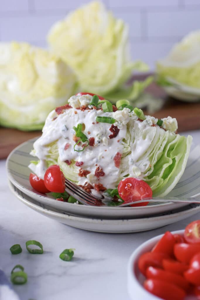 Steakhouse Blue Cheese Dressing on a wedge salad with blue cheese crumbles, bacon and green onions.