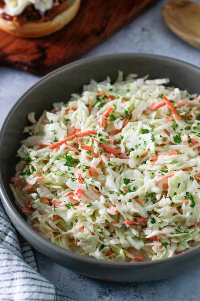 Sweet Creamy Coleslaw in a bowl garnished with fresh parsley.
