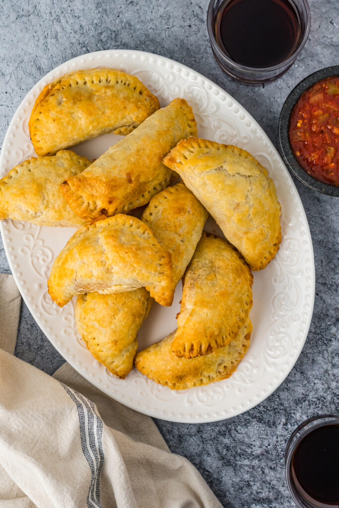 Taco Empanadas on a white oval plate with salsa for dipping.