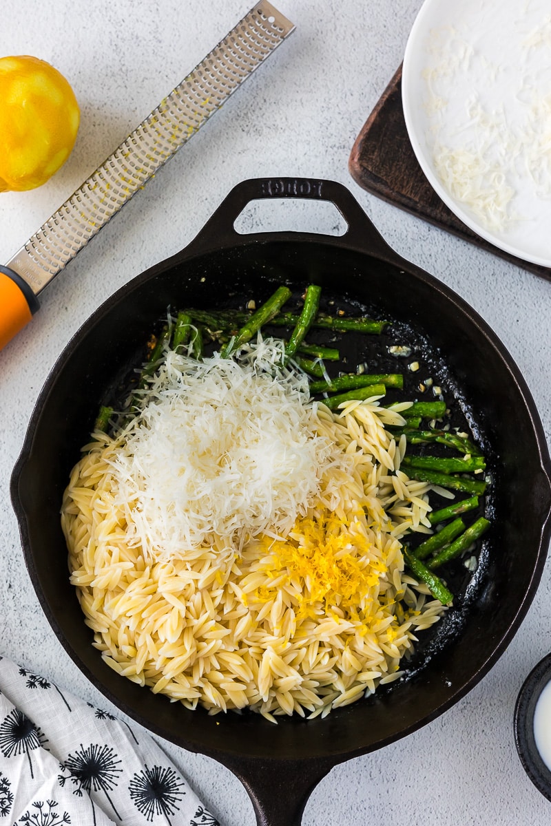 cast iron skillet with asparagus, cooked orzo, parmesan cheese and lemon zest.
