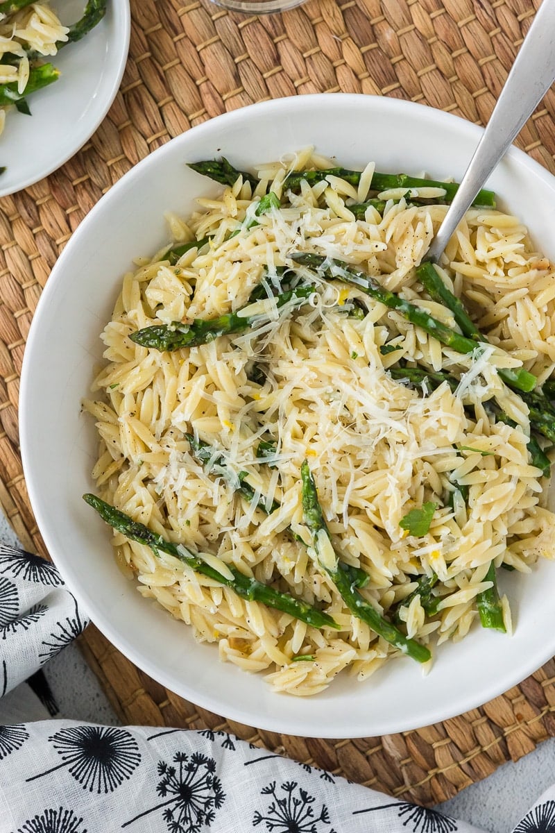 Asparagus Orzo in white bowl with spoon with napkin.