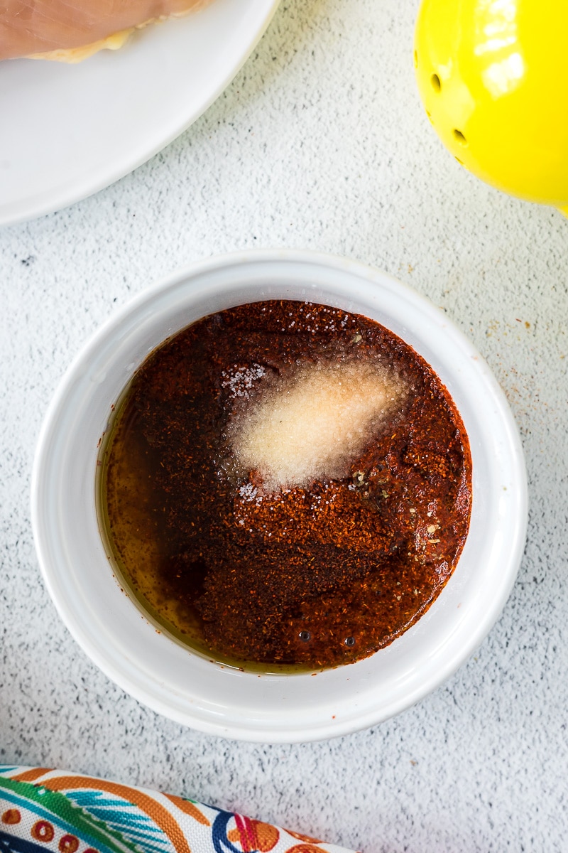 Chicken marinade in a white bowl before whisking it up and adding to the chicken.