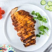 Chicken breast with a Mexican spice blend on a plate with salad vegetables.