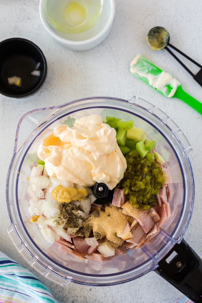 Ingredients for ham salad inside of a food processor before it has been processed.