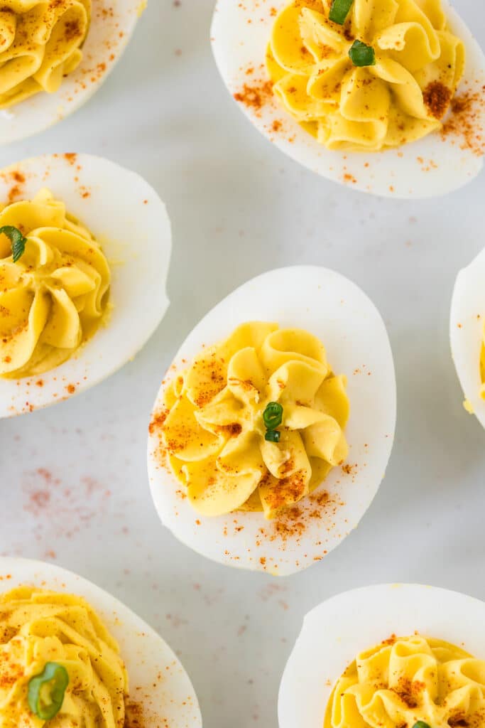 Deviled Eggs on a white plate garnished with paprika and green onions.