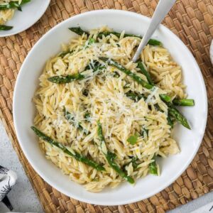 Asparagus orzo in a white bowl with a spoon.