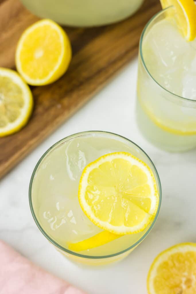 Fresh Squeezed Lemonade in two glass cups with lemons as garnish.