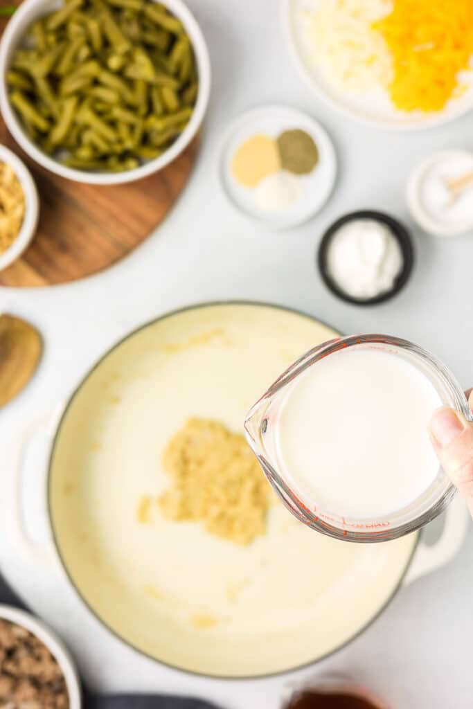 Half and half being added to a pan to make bechamel sauce for hamburger green bean casserole.