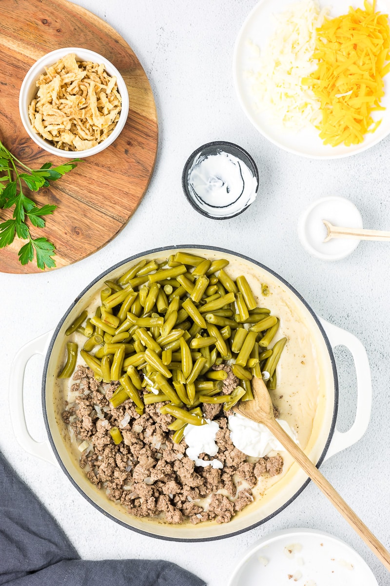 Ingredients for hamburger green bean casserole in a pan.