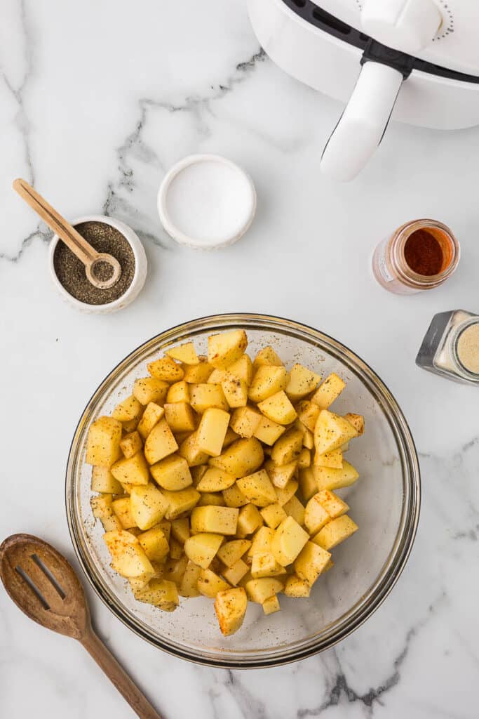 Diced potatoes coated in spices before cooking in the air fryer.