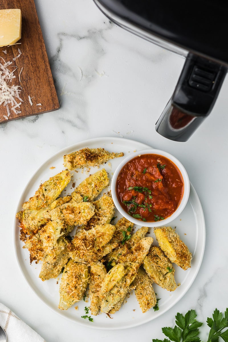 Air Fryer Artichoke Hearts on a plate with marinara sauce for dippings.