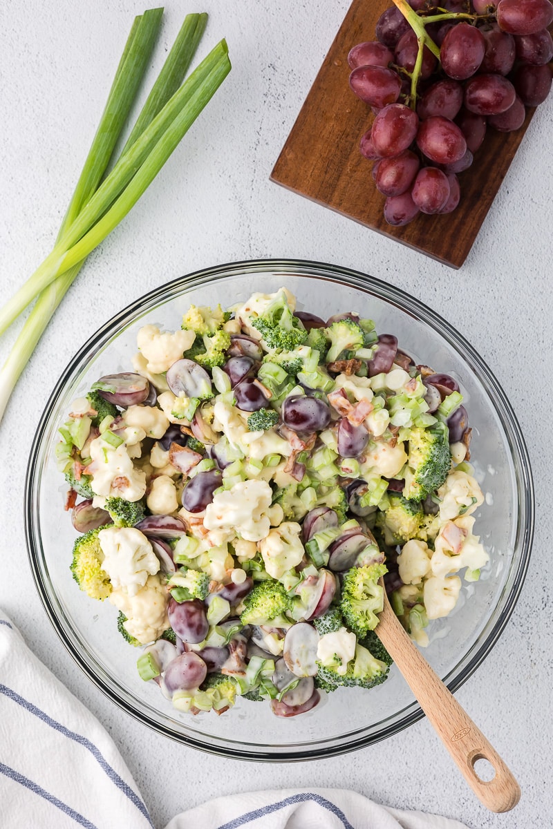 A mixing bowl with cauliflower and grape salad ingredients.