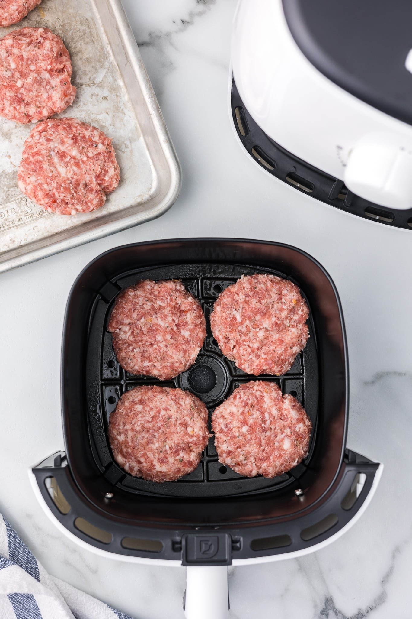 Sausage patties in an air fryer basket before they are cooked.