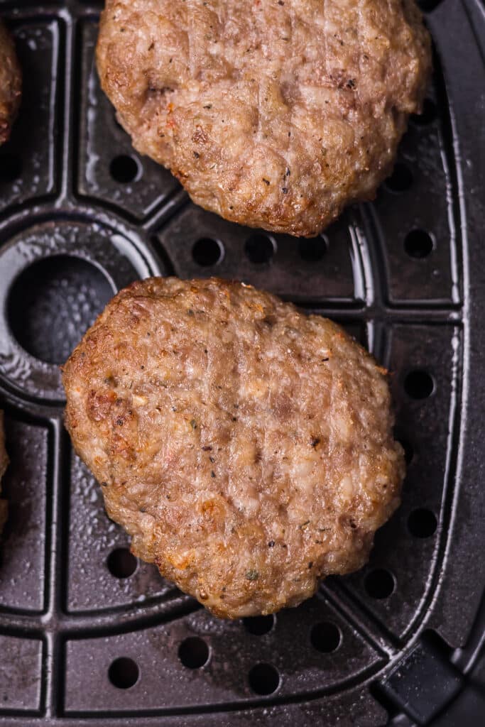 Cooked sausage in an air fryer basket.