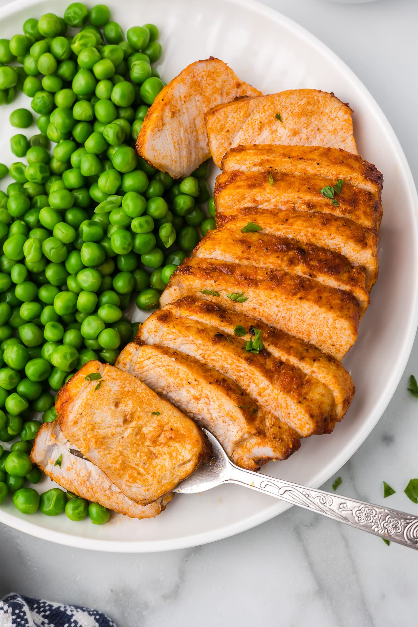 Air fryer pork chops on a plate with green peas.