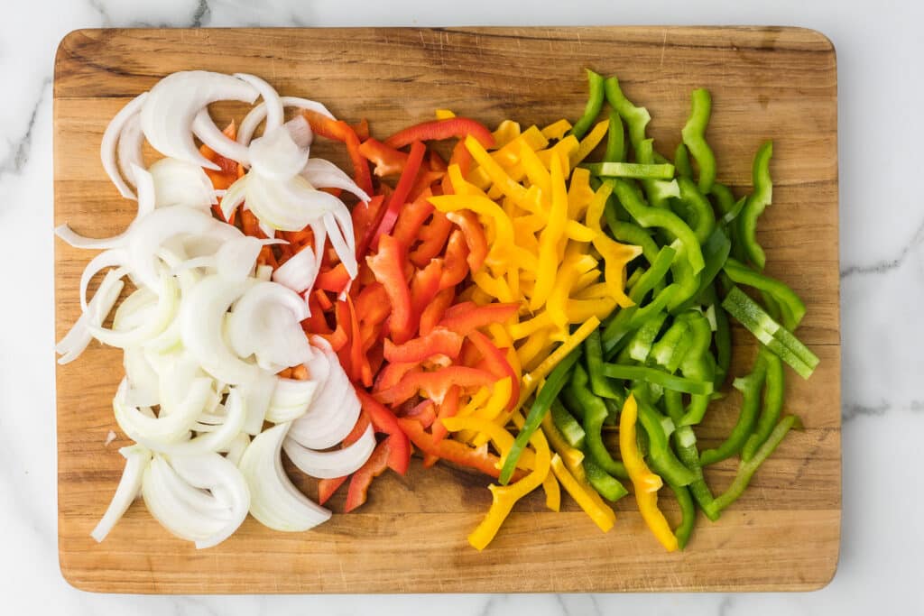 Sliced red, yellow and green bell peppers and onions.