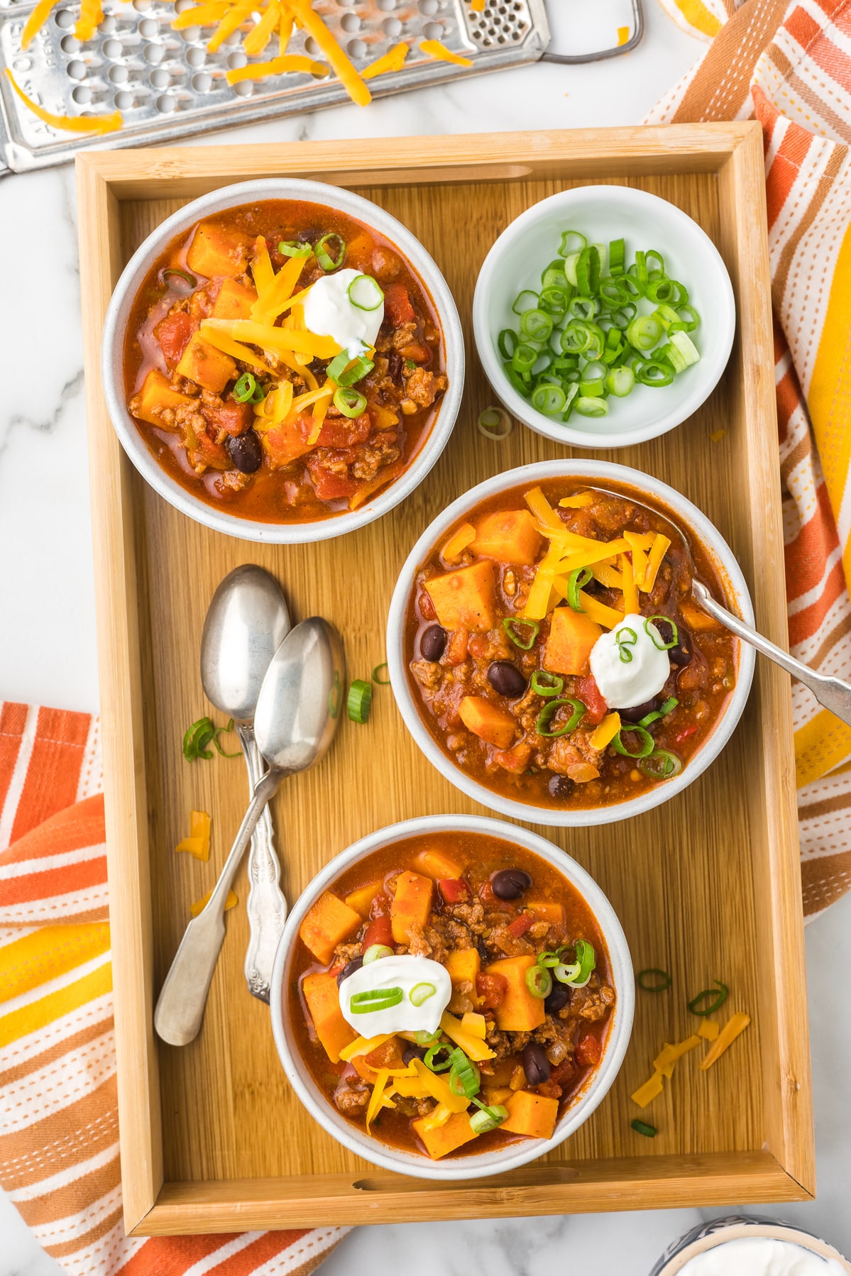Three bowls of chili with toppings.